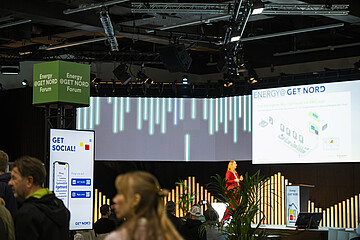 Besuchte Fachveranstaltung auf einer Bühne des Energy@GET NORD Forums. Im Vordergrund sitzen und stehen Teilnehmende, während auf der Bühne eine Präsentation mit großer Leinwand gezeigt wird.