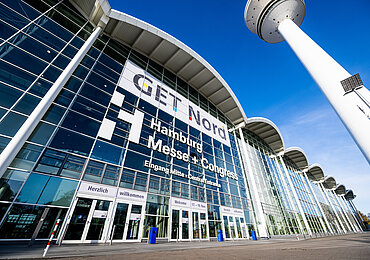 Der Eingang Mitte vom Zentralgebäude der Messe ist von außen aus der Froschperspektive abgebildet. Auf der Glasfront steht Get Nord und Hamburg Messe und Congress.