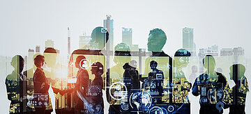 „Silhouetten von Menschen vor einer urbanen Kulisse mit überlagerten digitalen Symbolen wie E-Mail-Icons, Zahnrädern und Diagrammen – Darstellung von technologischer Vernetzung und moderner Zusammenarbeit in städtischer Umgebung.“