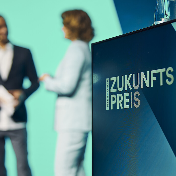 Podium mit dem Schriftzug „Zukunftspreis“ und zwei Personen im Hintergrund während einer Bühnensituation auf der INTERNORGA.